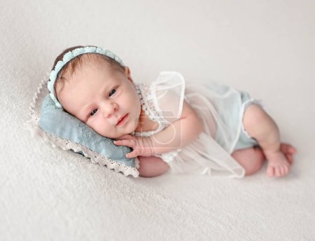 Photo for Newborn baby girl with beautiful eyes lying on pillow wearing wreath. Cute infant child kid studio portrait - Royalty Free Image