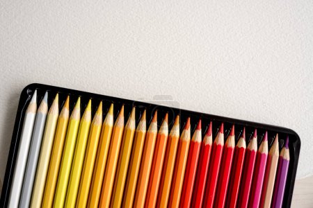 Foto de Caja con lápices de colores en papel acuarela con espacio de copia de primer plano. Paleta de crayones multicolor para inspiración artística - Imagen libre de derechos