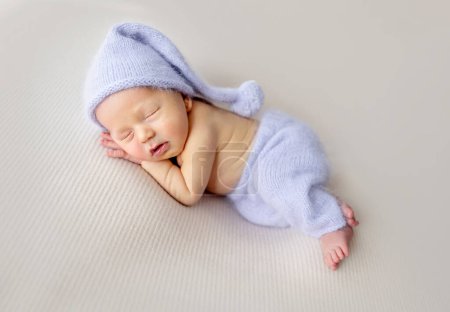 Photo for Newborn baby boy with bunny toy sleeping wearing knitted pants and hat. Little infant child napping - Royalty Free Image