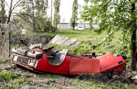Foto de Vehículo rojo abandonado dañado en una zona residencial destruida durante la guerra rusa en Ucrania. Vehículo civil tras atentado terrorista con cohetes militares en Kharkiv - Imagen libre de derechos