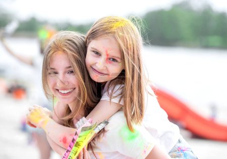 Photo for Pretty girls sisters in indian Holi festival with colorful powder smiling and having fun. Female teenager and preteen child friends enjoying holiday - Royalty Free Image