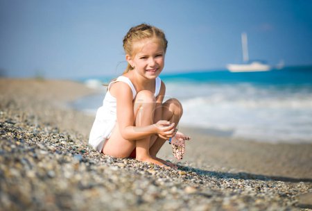 Photo for Girl with pebbles in her hands on the beach - Royalty Free Image