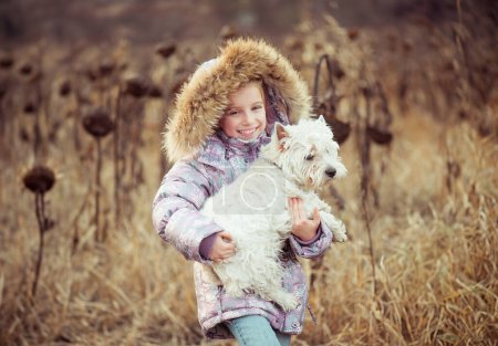 Foto de Chica feliz con su perro en un campo en otoño - Imagen libre de derechos