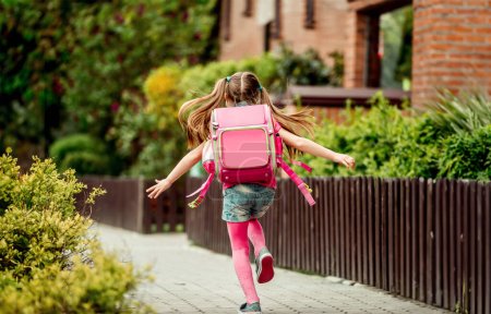 Foto de Una niña con una mochila corriendo a la escuela. vista posterior - Imagen libre de derechos