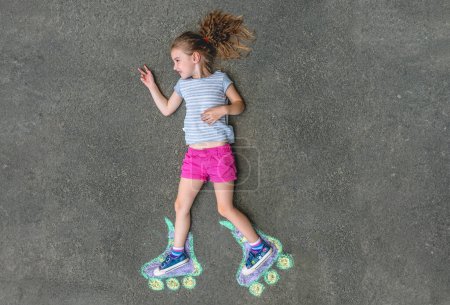Foto de Chica dulce en patines pintados con tiza sobre asfalto. vista superior - Imagen libre de derechos