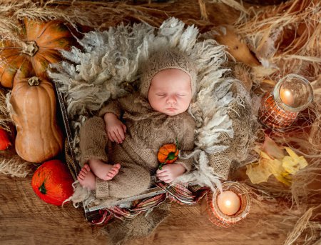 Photo for Newborn sleeping framed by orange pumpkins and candle, top view - Royalty Free Image