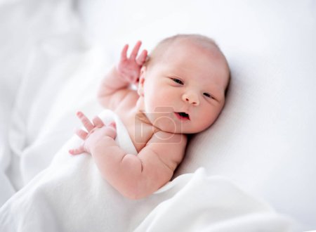 Foto de Linda niña recién nacida acostada en la cama y durmiendo sosteniendo sus manos cerca de la cabeza. Dulce bebé descansando en casa - Imagen libre de derechos