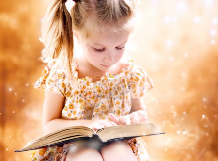 Photo for Sweet happy little girl reading a book - Royalty Free Image