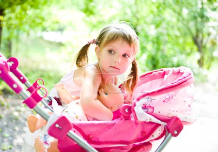 Photo for Cute little girl with her toy carriage - Royalty Free Image