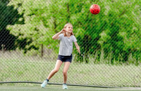 Téléchargez les photos : Jolie enfant fille attraper le ballon de football défendant but. Mignon enfant femelle au terrain de socker jouer - en image libre de droit