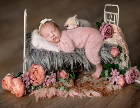 Photo for Newborn baby girl with a kitty sleeping in a tiny bed with peony flower decoration. Cute infant child kid napping floral spring portrait - Royalty Free Image