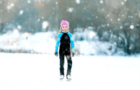 Téléchargez les photos : Joyeux petite fille en costumes thermiques patiner en plein air - en image libre de droit