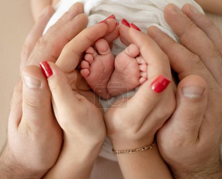Foto de Adorable bebé recién nacido pies en manos de la madre y el padre de primer plano. Los padres se preocupan por las lindas piernas diminutas del bebé con amor y ternura - Imagen libre de derechos