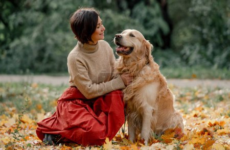 Téléchargez les photos : Jeune femme dans le parc d'automne avec son chien golden retriever - en image libre de droit
