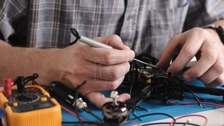 Photo for Repair Man Soldering Wires And Microchip Board On FPV Hobby Drone At Service Center - Royalty Free Image