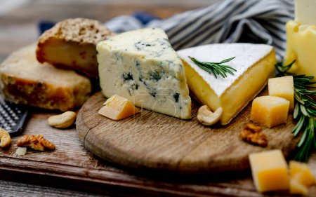 Téléchargez les photos : Assiette au fromage avec des noix et du miel est disposée sur un panneau en bois - en image libre de droit