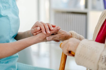 Photo for NurseS Hand Holding Elderly WomanS Hand With A Cane And NurseS Hand Holding Pills That Elderly Woman Is Taking, Are Captured In Close-Up - Royalty Free Image