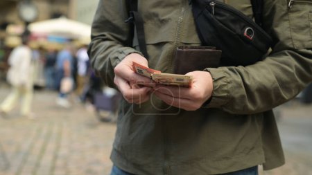 Photo for Man On Street Pulls Out Euro From Wallet And Counts Them - Royalty Free Image