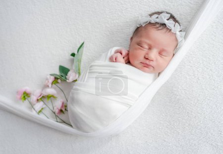 Foto de Recién nacido chica durmiendo en un babero en tonos blancos durante una sesión de fotos del bebé en el estudio - Imagen libre de derechos