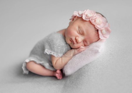 Téléchargez les photos : Fille nouveau-né dort en robe grise pendant la séance photo de bébé en studio - en image libre de droit