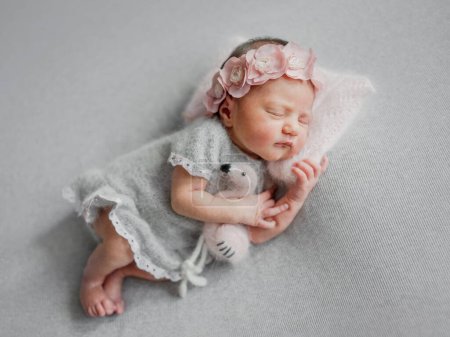 Téléchargez les photos : Fille nouveau-né dort en robe grise avec jouet Flamingo pendant la séance photo de bébé en studio - en image libre de droit