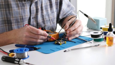 Photo for Master Technician Uses Multimeter To Check Electrical Circuit For Electronics Repair In Service Center - Royalty Free Image