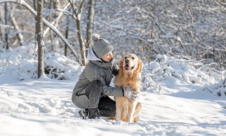 Téléchargez les photos : Fille, Adolescent, Et Golden Retriever Jouez joyeusement avec la neige dans la forêt d'hiver - en image libre de droit