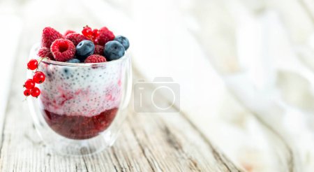 Foto de Postre de yogur con semillas de chía, frambuesas y arándanos sobre un fondo de madera viejo. vista superior - Imagen libre de derechos