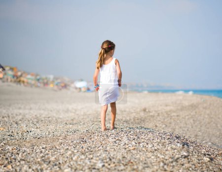 Téléchargez les photos : Retour d'une petite fille en vacances à la plage tropicale - en image libre de droit