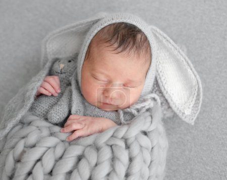 Téléchargez les photos : La jeune fille au chapeau de lapin dort pendant la séance de photo de bébé dans le studio - en image libre de droit