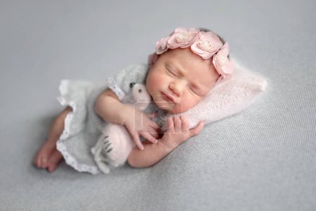 Téléchargez les photos : Fille nouveau-né dort en robe grise avec jouet Flamingo pendant la séance photo de bébé en studio - en image libre de droit