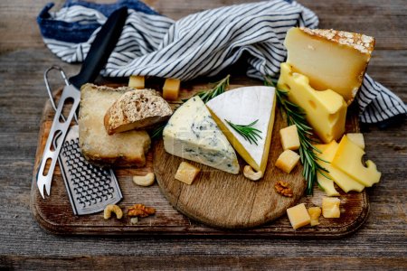 Téléchargez les photos : Assiette au fromage avec des noix placées sur un panneau en bois est une délicieuse collation - en image libre de droit