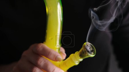 Photo for Woman Smokes Cannabis With Bong In Close-Up View - Royalty Free Image
