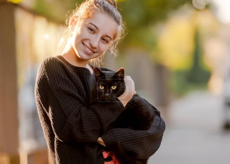 Foto de Adolescente chica sostiene negro gato en su manos un retrato con un mascota en casa - Imagen libre de derechos