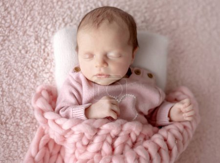 Téléchargez les photos : Bébé fille en tenue rose dort pendant la séance photo nouveau-né en studio - en image libre de droit