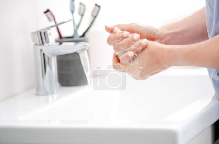Foto de Chica lava las manos con jabón líquido en bañera prístina - Imagen libre de derechos