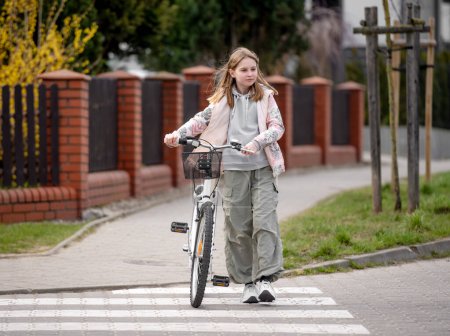 Téléchargez les photos : Fille traverse la route sur la traversée piétonne avec vélo au printemps - en image libre de droit