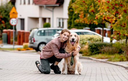Photo for Preteen teen girl wear on golden retriever dog lace outdoors. Pretty kid child with purebred pet doggy walking at street - Royalty Free Image