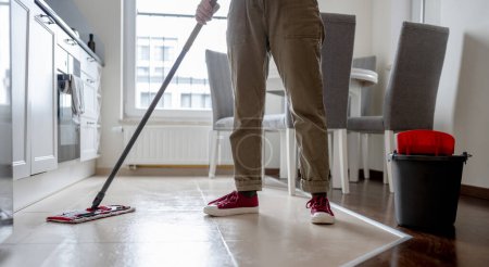 Photo for Woman Mops Kitchen Floor With Mop - Royalty Free Image