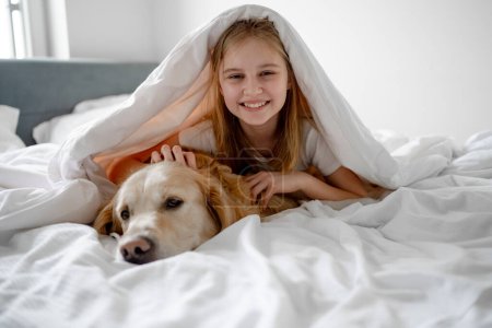 Téléchargez les photos : Fille repose sous la couverture avec son chien Golden Retriever - en image libre de droit