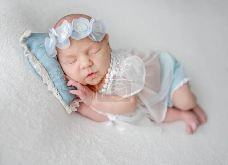 Téléchargez les photos : Nouvelle-née fille en dentelle robe dort dans des tons blancs et bleus Photo - en image libre de droit