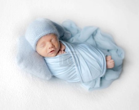 Photo for Newborn Baby In White Jumpsuit Sleeps During Studio Photoshoot - Royalty Free Image