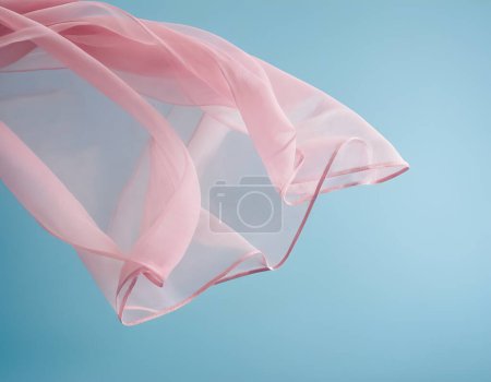 Téléchargez les photos : Onde de tissu rose volant isolée sur fond bleu, ondulation fluide tissu flottant de soie - en image libre de droit