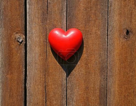 Coeur rouge vif comme symbole d'amour et d'amitié sur le fond d'un mur ou d'une clôture en bois