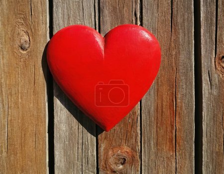 Téléchargez les photos : Coeur en bois rouge vif comme symbole d'amour et d'amitié sur le fond d'un mur ou d'une clôture en bois - en image libre de droit