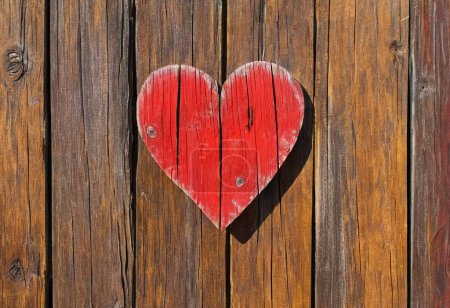 Corazón rojo brillante como símbolo de amor y amistad sobre fondo de madera