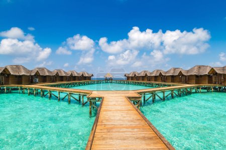 Water Villas (Bungalows) y puente de madera en la playa tropical de las Maldivas en el día de verano