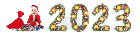 Téléchargez les photos : Garçon Père Noël tenant un sac de Noël et 2023 nombre fait par branches arbre de Noël isolé sur fond blanc - en image libre de droit