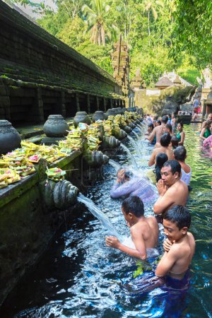 Foto de BALI, INDONESIA - 28 DE FEBRERO DE 2020: El pueblo balinés reza en el agua bendita de la piscina en el Templo Empul Pura Tirta en Bali, Indonesia - Imagen libre de derechos