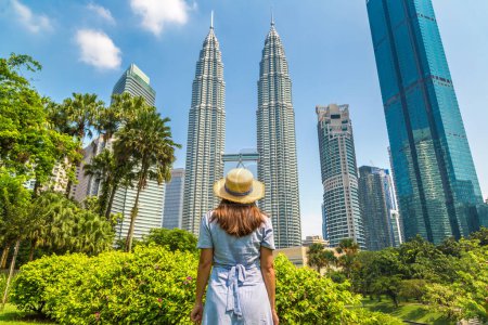 Photo for KUALA LUMPUR, MALAYSIA - FEBRUARY 25, 2020: Woman traveler at  Petronas Tower in a sunny day in Kuala Lumpur, Malaysia - Royalty Free Image